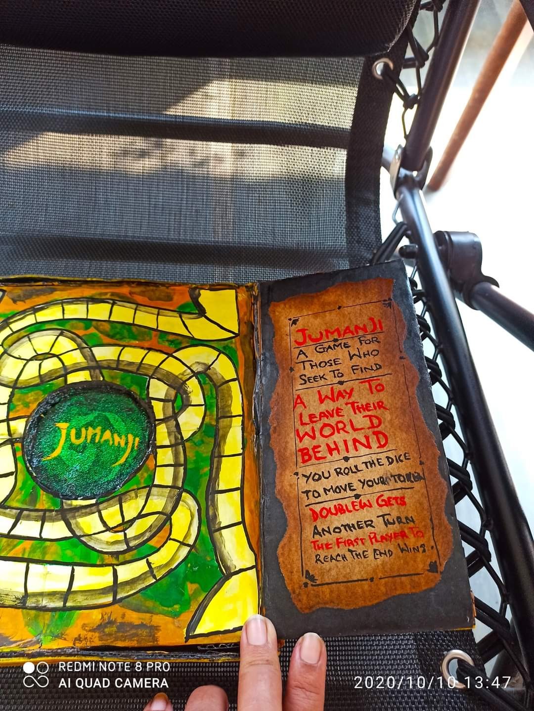 Jumanji game interior with the spiral game board visible and the hand-lettered instruction insert: "A game for those who seek to find a way to leave their world behind"